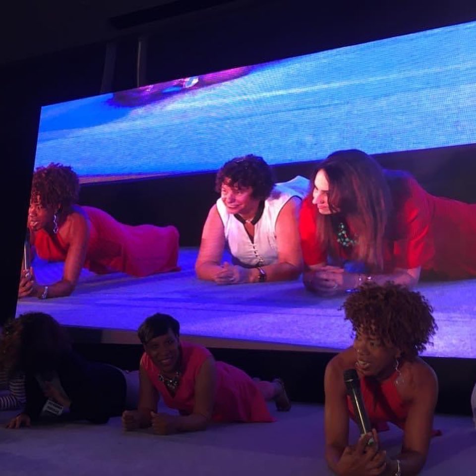 Candice Camille on a stage planking with others.